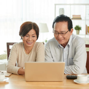 Cheerful senior couple using laptop to research bioidentical hormone therapy.