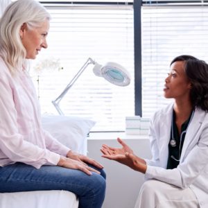 Doctor speaking with mature woman during visit about hormone replacement therapy.
