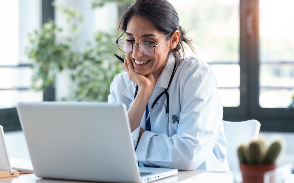 Smiling Female Doctor Working With Her Laptop In The Consultation Picture Id1249601315
