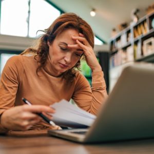 Woman experiencing toxic stress, looking at financial documents.
