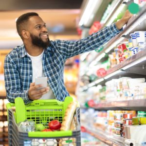 Black Male Shopping Groceries In Supermarket Taking Product off of shelf