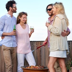 Backyard barbecue with four smiling individuals holding drinks and considering a liver detox.