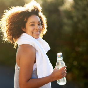 Young women in exercise attire, smiling and holding a water bottle.