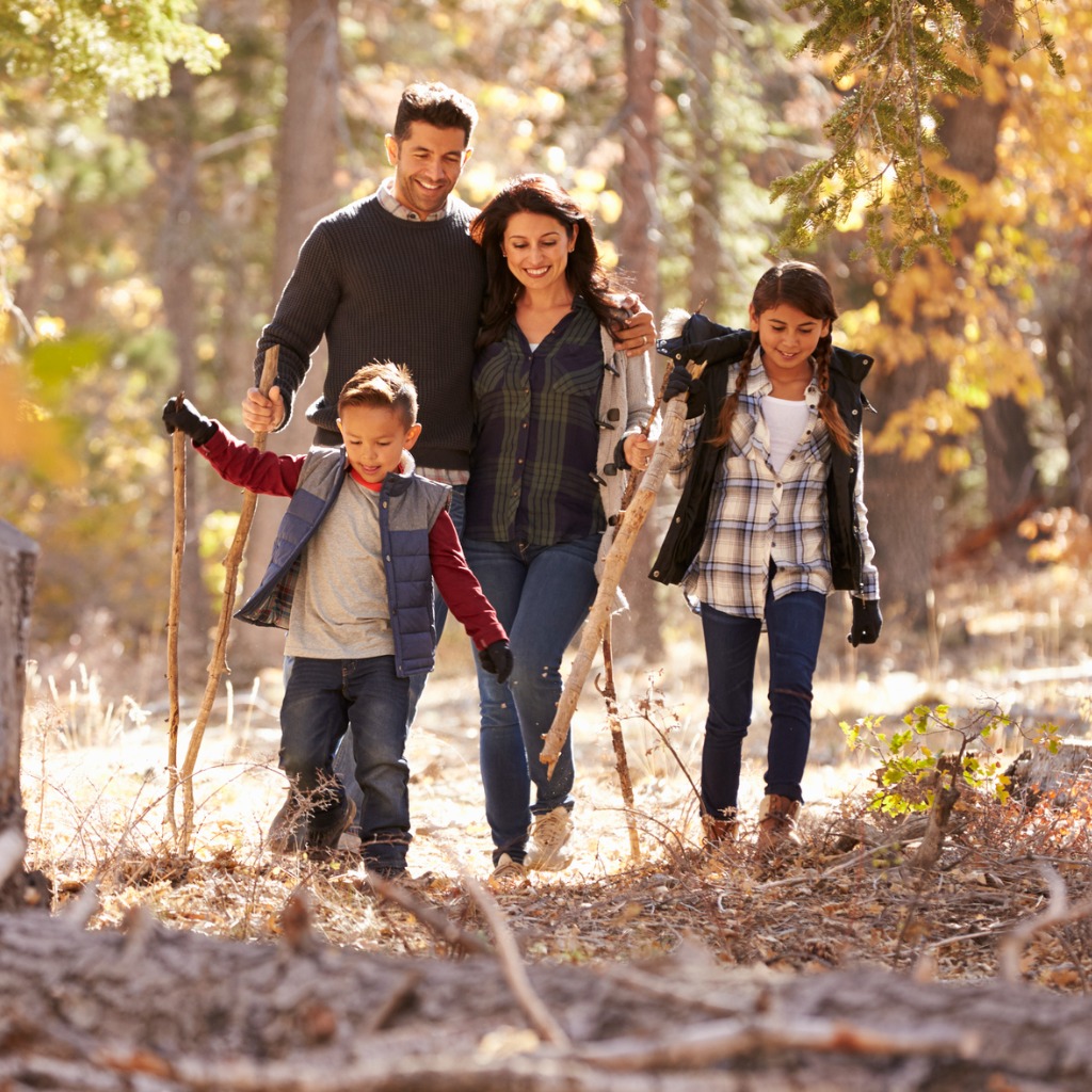 Happy Hispanic Family With Two Children Walking In A Forest